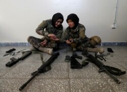 Female soldiers Karima Mohamadi, left, and Tamana, from the Afghan National Army, clean their weapons at the Kabul Military Training Center in Kabul, Oct. 26, 2016.