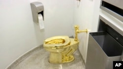 FILE - An 18-karat toilet, titled "America," by Maurizio Cattelan in the restroom of the Solomon R. Guggenheim Museum in New York, Sept. 16, 2016. Thieves have stolen the solid gold toilet from Blenheim Palace, the birthplace of Winston Churchill.