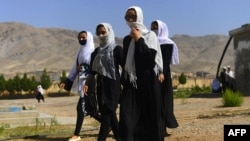Siswa perempuan Afghanistan menutupi wajah mereka dengan syal saat mereka berjalan di dalam kompleks sekolah mereka setelah dibuka kembali, yang sebelumnya ditutup karena pandemi virus corona COVID-19, di Herat pada 23 Agustus 2020. (Foto: AFP)