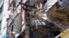 A woman, top left, stands at a balcony of her apartment near a lamp post jumbled with electric cables in Rangoon, Burma, Jan. 27, 2014.