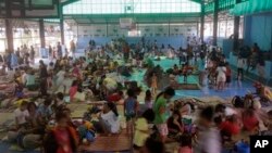 FILE - Residents rest in an evacuation center at suburban Quezon city northeast of Manila, Philippines after fleeing their homes in anticipation of typhoon Hagupit, Dec. 9, 2014.