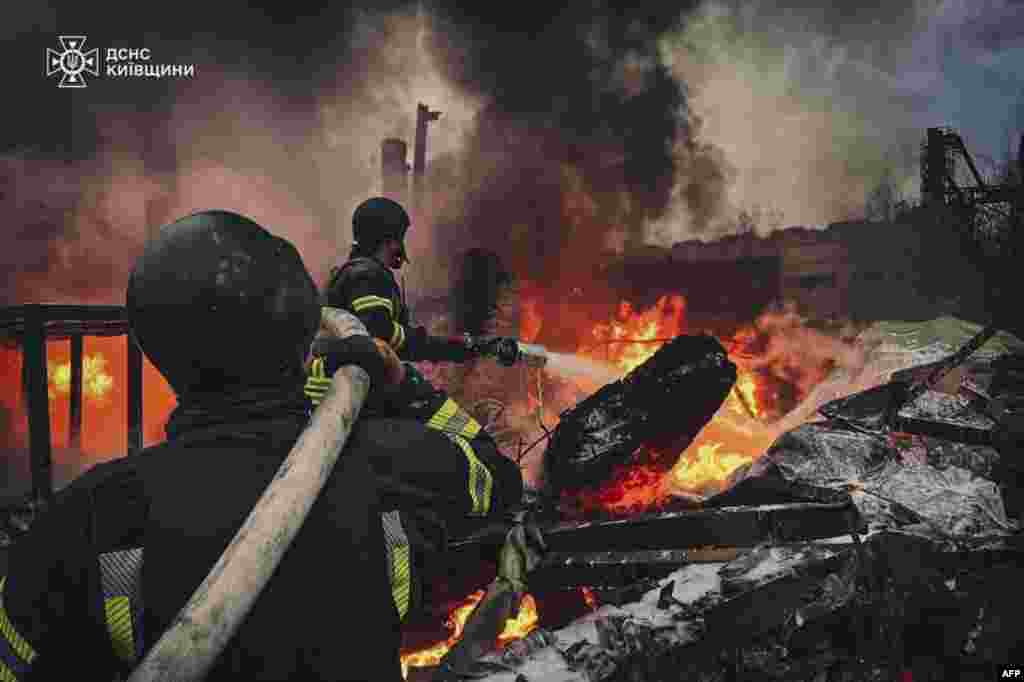 This handout photograph taken and released by the State Emergency Service of Ukraine shows firefighters extinguishing fire following a Russian strike in Brovary, near Kyiv.