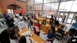 FILE - In this Tuesday, Oct. 6, 2015, photo, job applicants fill out and turn in forms during a job fair at Dolphin Mall in Miami. 