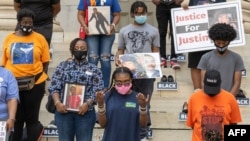 People gather at Brooklyn Borough Hall for a vigil against gun violence on July 8, 2020 in the Brooklyn borough of New York City. 101 pairs of shoes and a casket are laid out to represent the 101 shooting victims over the past week.