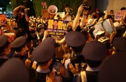 Police officers try to push back protesters outside the stadium Olympic Stadium in Tokyo, Japan - July 23, 2021.