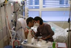 FILE - Amelie and Ludo Khayat hold each other during a visit at the COVID-19 intensive care unit of the la Timone hospital in Marseille, southern France, Thursday, Dec. 23, 2021.