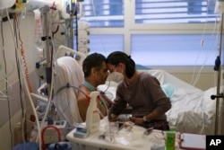 FILE - Amelie and Ludo Khayat hold each other during a visit at the COVID-19 intensive care unit of the la Timone hospital in Marseille, southern France, Thursday, Dec. 23, 2021.