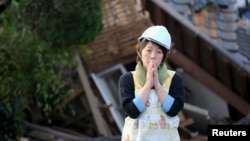 A woman reacts in front of collapsed house caused by an earthquake in Mashiki town, Kumamoto prefecture, southern Japan, in this photo taken by Kyodo, April 16, 2016. 