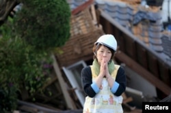 A woman reacts in front of collapsed house caused by an earthquake in Mashiki town, Kumamoto prefecture, southern Japan, in this photo taken by Kyodo, April 16, 2016.