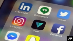 The Vero app, center, is displayed on an iPhone in New York, March 1, 2018. Instagram users fed up with ads, with the end of chronologically displayed posts and the lack of granular privacy controls are flocking to Vero.