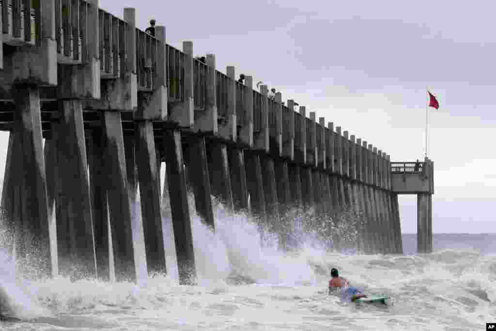 A surfer makes his way out into the water as a subtropical approaches in Pensacola, Florida.