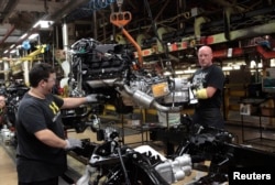 FILE - Chrysler Group LLC assembly workers lower an engine on to the frame of a 2014 Ram 1500 pickup truck on the assembly line at the Warren Truck Plant in Warren, Michigan, Sept. 25, 2014.