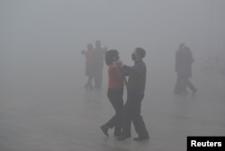 People wearing masks dance at a square amid heavy smog during a polluted day in Fuyang, Anhui province, China, January 3, 2017.