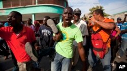 Anti-government protesters carry the body of a demonstrator who was shot to death during clashes with the National Police in Port-au-Prince, Haiti, Dec. 13, 2014.