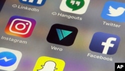 The Vero app, center, is displayed on an iPhone in New York, March 1, 2018. Instagram users fed up with ads, with the end of chronologically displayed posts and the lack of granular privacy controls are flocking to Vero.