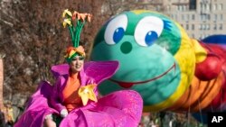 FILE - A woman in a flower costume marches in front of the Wiggle Worm balloon during last year's Macy's Thanksgiving Day Parade, November 28, 2019, in New York.