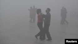 People wearing masks dance at a square amid heavy smog during a polluted day in Fuyang, Anhui province, China, Jan. 3, 2017. Fuyang is about 700 miles south of Beijing.