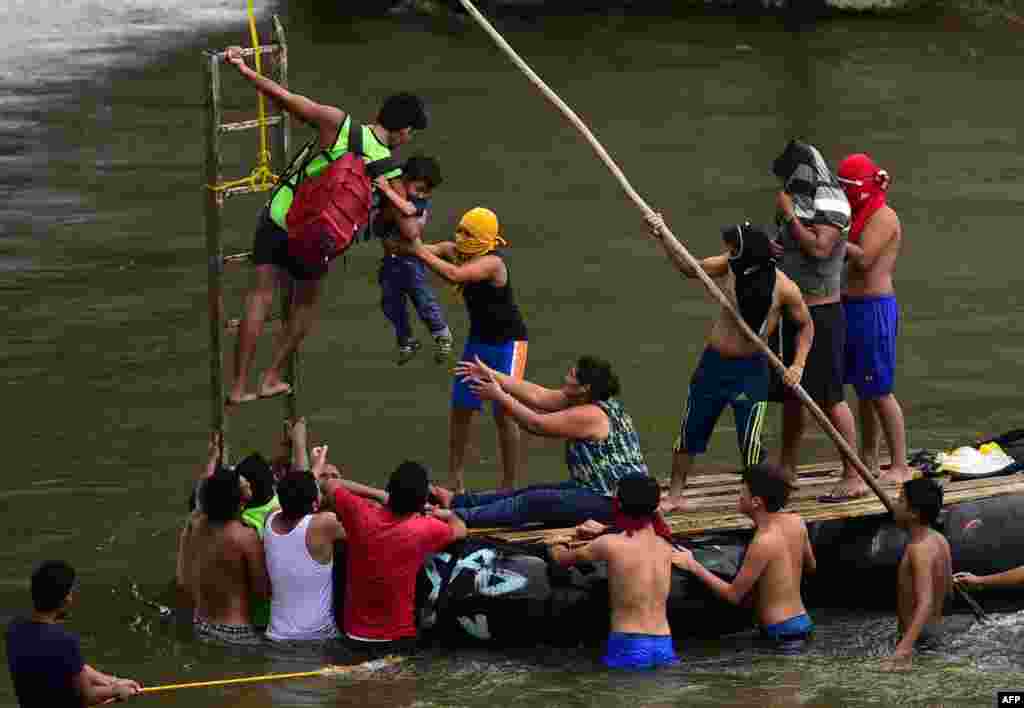 Migrantes hondureños que se dirigen en una caravana hacia Estados Unidos ayudan a un hombre con un niño a bajar hacia el río Suchiate desde el puente internacional en la frontera entre México y Guatemala, en Ciudad Hidalgo, estado de Chiapas, México, el 2