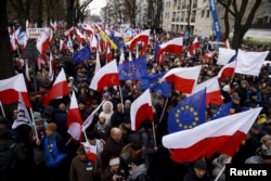 People hold European Union and Polish national flags during an anti-government demonstration in front of the Constitutional Court in Warsaw, Poland, Dec. 12, 2015.