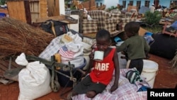FILE: Zimbabwean children sit among salvaged possessions at a transit camp for over 100 families displaced by floods near the Tokwe-Mukorsi dam about 430km (267 miles) south of Harare, Feb. 13, 2014.