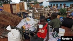 Des enfants zimbabwéens sont assis au milieu des biens récupérés dans un camp de transit après des inondations près du barrage Tokwe-Mukorsi, à environ 430 km au sud de Harare, 13 février 2014.