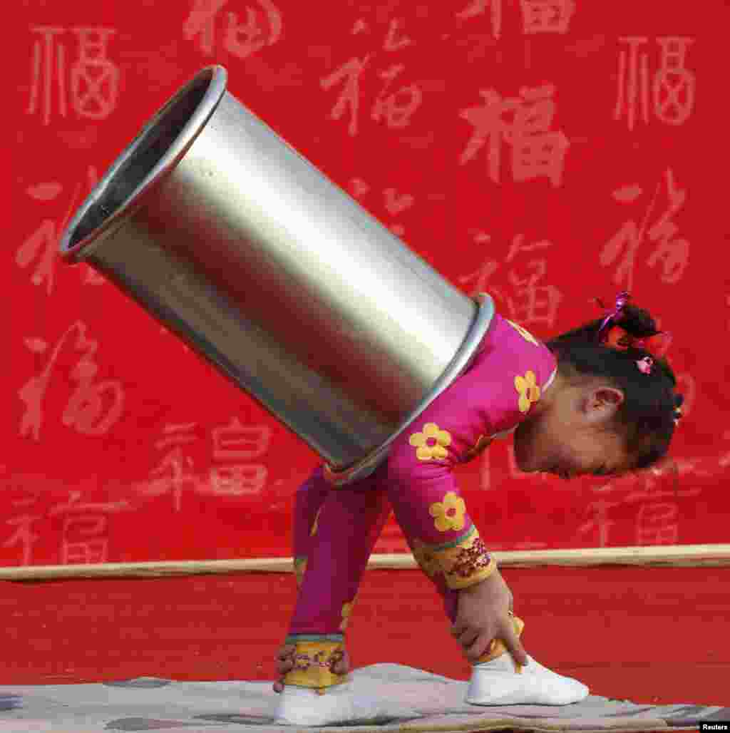 Seorang gadis cilik menampilkan pertunjukan akrobatik di sebuah kuil di Taman Ditan, yang juga dikenal sebagai Kuil Bumi, di Beijing, Tiongkok. Tahun Baru Imlek, atau Festival Musim Semi, dimulai pada tanggal 10 Februari dan menandai awal Tahun Ular menurut zodiak Cina.