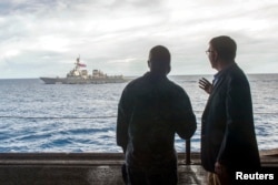 FILE - U.S. Secretary of Defense Ash Carter, right, speaks with U.S. Navy Cmdr. Robert Francis Jr., as Carter and Malaysian Defense Minister Hishammuddin Hussein (not pictured) visited the USS Theodore Roosevelt aircraft carrier in the South China Sea.