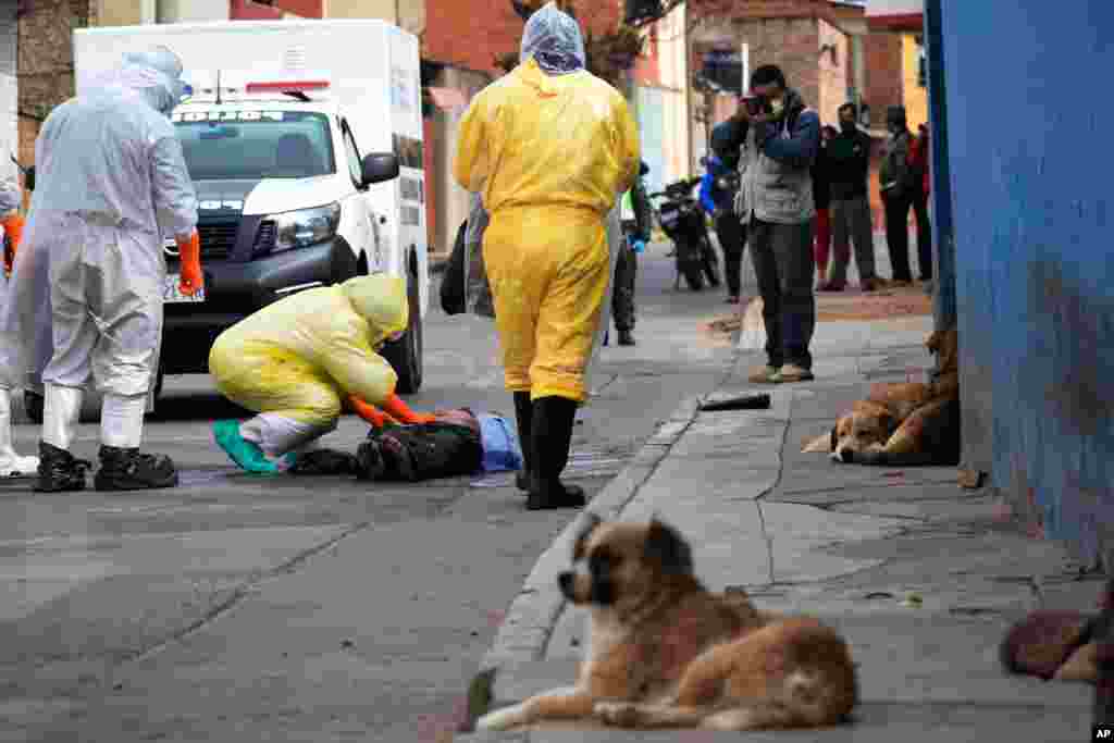 Health workers recover the body of a street vendor who was found dead at dawn by his neighbors in the Cerro San Miguel neighborhood of Cochabamba, Bolivia, July 25, 2020.