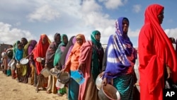 FILE - Newly-arrived women who fled drought queue to receive food distributed by local volunteers at a camp for displaced persons in the Daynile neighborhood on the outskirts of the capital Mogadishu, in Somalia, May 18, 2019. 