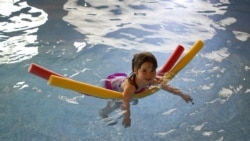 Girl in Swimming Pool with Floating Noodles