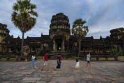 FILE- People walk in the grounds of the Angkor Wat temple in Siem Reap province on November 29, 2020. (Photo by TANG CHHIN Sothy / AFP)