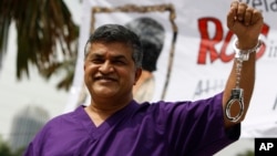 FILE - Malaysian cartoonist Zulkiflee Anwar Alhaque, better known as Zunar, wearing a prison outfit and plastic handcuffs poses for photographers prior to launching his book in Petaling Jaya, Malaysia.