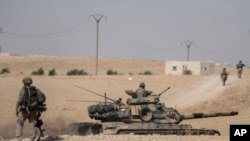 FILE - FILE - Turkish tanks and troops are deployed near the Syrian town of Manbij, Syria, Oct. 15, 2019.