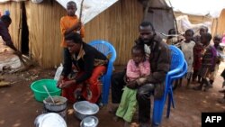 A family of refugees from the Democratic Republic of Congo sit by their makeshift hut at the Kenani refugee transit camp in Nchelenge, Oct. 30, 2017, during a visit by Zambian President Edward Lungu.