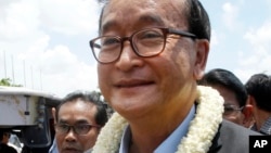 FILE - In this Aug. 16, 2015, file photo, Sam Rainsy, leader of the opposition Cambodia National Rescue Party, greets his party supporters upon his arrival at Phnom Penh International Airport in Phnom Penh, Cambodia. The Phnom Penh Municipal Court on Tuesday, Nov. 8, 2016, found Sam Rainsy, country's exiled opposition leader, guilty of defamation for alleging that a senior government official sought to inflate Prime Minister Hun Sen's online popularity by buying "likes" for his Facebook page. (AP Photo/Heng Sinith, File)