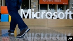 Un homme passe devant une enseigne Microsoft installée pour la conférence Microsoft BUILD au Moscone Center de San Francisco le 28 avril 2015.