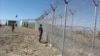 پاک افغان سرحد پر نصب کی جانے والی آہنی باڑ کے قریب ایک سیکیورٹٰی اہل کار سرحد پار کا جائزہ لے رہا ہے۔ فائل فوٹو