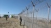 FILE - Pakistani soldiers stand guard at a fence between Pakistan and Afghanistan at Angore Adda, Pakistan, Oct. 18, 2017.