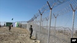 FILE - Pakistani soldiers stand guard at a fence between Pakistan and Afghanistan at Angore Adda, Pakistan, Oct. 18, 2017.