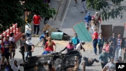 Los manifestantes antigubernamentales se enfrentan a las fuerzas de seguridad cuando muestran su apoyo a un aparente motín por parte de una unidad de la Guardia Nacional en el barrio de Cotiza en Caracas, Venezuela.