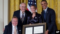 President Barack Obama, right, with former President George H. W. Bush, left, present the 5,000th Daily Point of Light Award to Floyd Hammer and Kathy Hamilton, center, from Union, Iowa, in the East Room of the White House, Jul. 15, 2013.