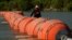 Un kayakista pasa junto a grandes boyas que se utilizan como barrera fronteriza flotante en el río Grande, el 1 de agosto de 2023, en Eagle Pass, Texas.