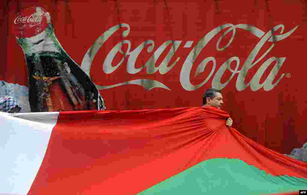 A pro-independence demonstrator passes by a Coca-Cola poster as he helps to carry a big Ikurrina (Basque flag) to protest in favor of the Basque flag and against the Spanish flag during local festivities in the northern Spanish Basque city of Bilbao.