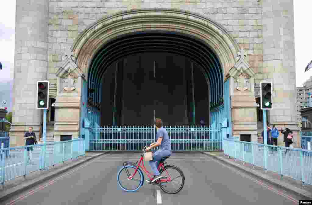 A cyclist looks toward Tower Bridge while it is stuck in the open position because of a technical issue, in London, Aug. 9, 2021.