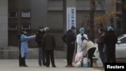 Petugas medis dan keamanan mencegat anggota keluarga dan memberikan instruksi agar tidak terlalu dekat dengan rumah sakit Jinyintan, di Wuhan, provinsi Hubei, tempat pasien yang terjangkit virus corona dirawat. (Foto: dok).