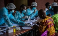 FILE - Health workers from the Guinean Ministry of Health prepare forms to register medical staff ahead of their anti-Ebola vaccines at the N'zerekore Hospital, Feb. 24, 2021.