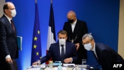 Presiden Prancis Emmanuel Macron (tengah) diapit oleh PM Jean Castex (kiri) dan Sekretaris Jenderal Istana Elysee Alexis Kohler (kanan) memulai pertemuan keamanan nasional untuk membahas spyware Pegasus di ruang Jupiter di Istana Kepresidenan Elysee di Paris, 22 Juli 2021. (AFP).