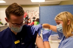 Mahasiswa kedokteran tahun keempat Anna Roesler sedang memvaksinasi Pfizer-BioNTech (COVID-19) di Indiana University Health, Methodist Hospital di Indianapolis, Indiana, AS. (Foto: REUTERS/Bryan Woolston)