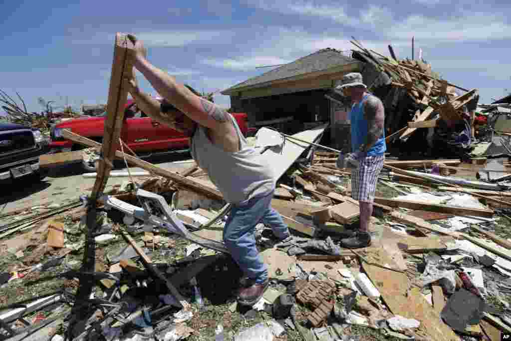 Chad Allcox, left, helps his friend Kevin McElvany, right, the home owner, clear debris away from his destroyed home from Monday's tornado, Moore, Oklahoma, May 22, 2013. 