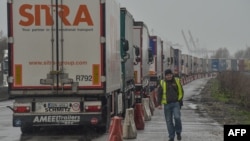 A driver walks next to trucks stuck in a traffic jam due a strike by customs agents, a few kilometers from the entrance to the Channel tunnel, in Loon-Plage, near Dunkirk, northern France, March 6, 2019.